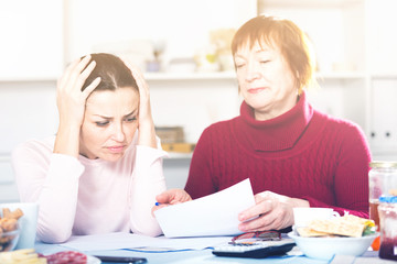 Upset mature woman and daughter with papers