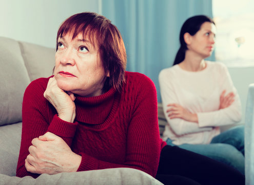 Unhappy women sitting at sofa after conflict at home