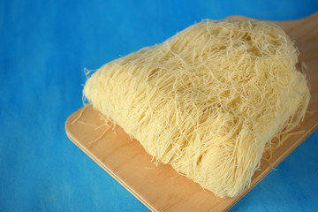 Kataifi dough on a wooden board on blue background