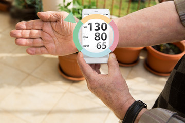 An elderly man measures blood pressure and pulse by mobile phone with augmented reality application.