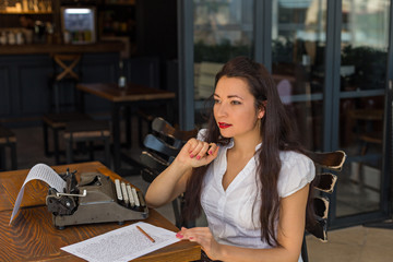 Female writer with vintage typewriter making notes in a coffee s