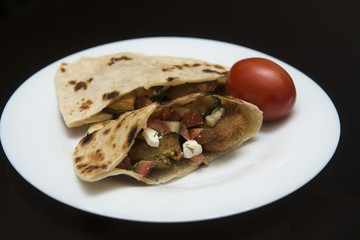 Pita bread filled with falafel and salad isolated on black