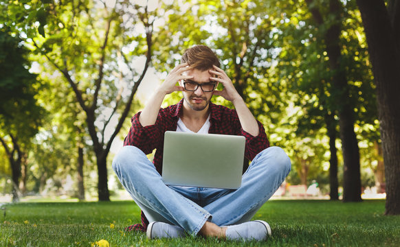 Desparate young man using a laptop outdoors