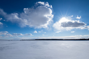 Beautiful winter landscape on the lake. The sun went behind the clouds. The rays of the sun Shine from behind the clouds.
