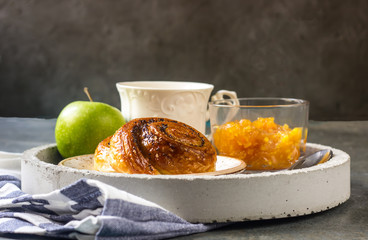 Breakfast on tray served with green tea, orange jam and buns