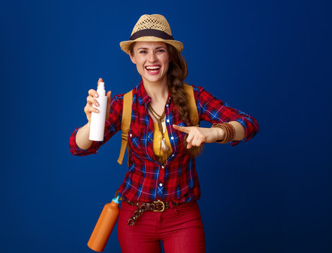 smiling active tourist woman pointing at bottle of spray