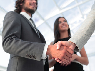 Businesspeople  shaking hands against room with large window loo