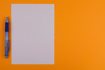 One multi color blue transparent ballpoint and white blank rectangle paper on background of orange paper with copy space