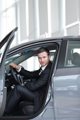 .successful businessman sitting behind the wheel of a new car