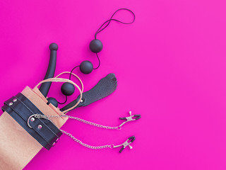 Sex toys are in a paper bag for purchases on a purple background. Image of the topic of shopping in the sex shop