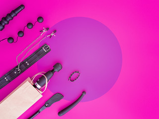 Different sex toys are on a background of fuchsia with a circle in the center. The massager is in a...
