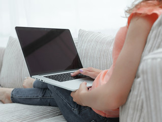 Fototapeta premium young woman working with laptop sitting on sofa