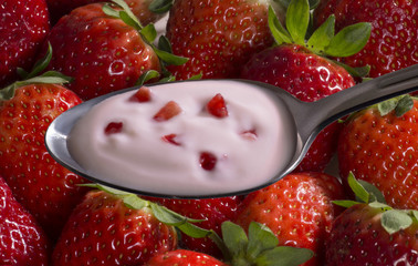 La cuchara con crema de yogurt de fresas y trozos.