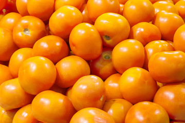 A pile of orange tomatoes in the store as background, texture