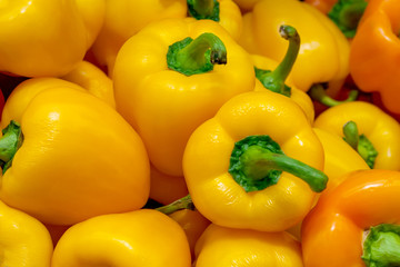 A pile of yellow bell peppers in the market (background, texture)