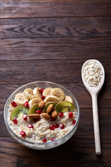 Diet breakfast oatmeal with fruits, bowl and spoon with oat flakes, selective focus, close-up