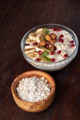 Diet breakfast oatmeal with fruits, bowl and spoon with oat flakes, selective focus, close-up