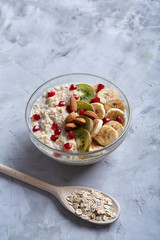 Diet breakfast oatmeal with fruits, bowl and spoon with oat flakes, selective focus, close-up