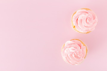 Cupcake with pink cream decoration on pink pastel background.