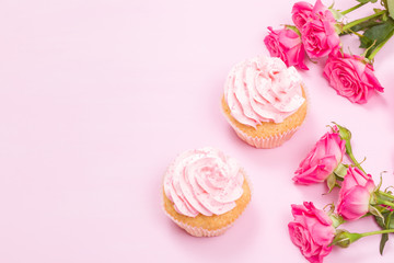 Cupcake with pink cream decoration and roses on pink pastel background.