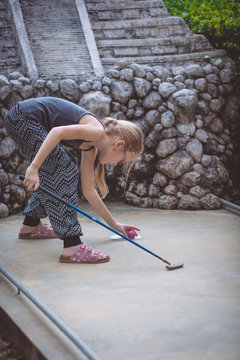 Happy little girl  playing mini golf.