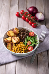 Buddha bowl with baked potatoes, lentils and spicy chickpeas, avocado, arugula, vegan, vegetarian healthy food