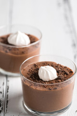 Chocolate mousse in a glasses on a white wood background.