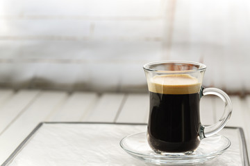 Espresso. Glass espresso cup with coffee beans on a light background