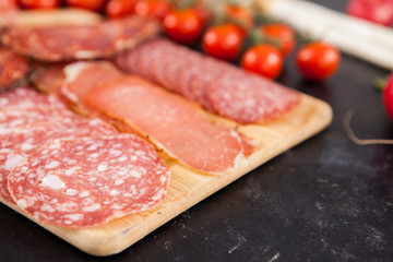 Meat appetizers next to cherry tomatoes, radish and green onion