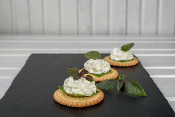 Bisquit cracker appetizers with cream cheese and basil topping