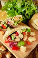 Caesar salad in pita bread on a wooden board