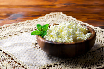 Cottage cheese in a wooden bowl on old wooden background with copy space for your text. Top view
