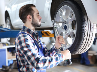 Young mechanic changing wheel at tire service
