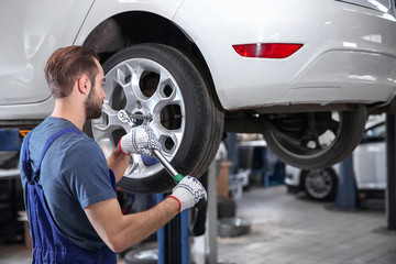 Young mechanic changing wheel at tire service