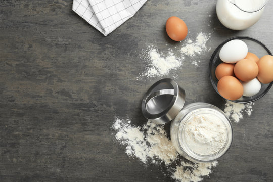 Jar with flour and eggs on grey background
