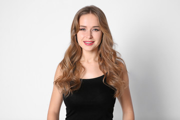 Obraz premium Portrait of young woman with long beautiful hair on light background