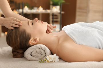 Fototapeta na wymiar Young woman enjoying face massage in spa salon
