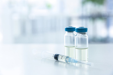 Vials and syringe with medicine on blurred background. Vaccination concept