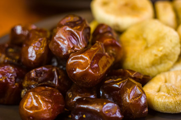 dried dates and figs in a ceramic plate on a wooden table