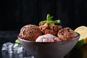 Portion of ice cream scoops with fruit on black