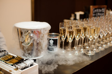 Steel ice bucket and set of glasses filled with champagne