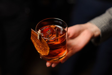 Male hand holding a glass of whiskey with ice