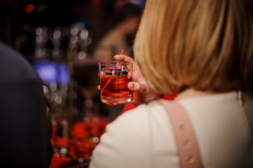 Back view of blonde woman holding a glass with summer cocktail