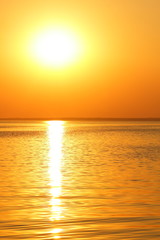 Obraz premium Orange sun over the sea horizon, beautiful sunset, copy space, landscape with a big sun, bloody horizon above the water surface, blank for the designer, orange pattern