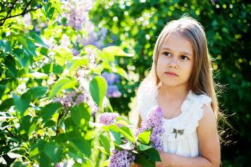 Beautiful girl enjoying the smell of lilacs. Cute model and flowers. The concept of aromatherapy and spring