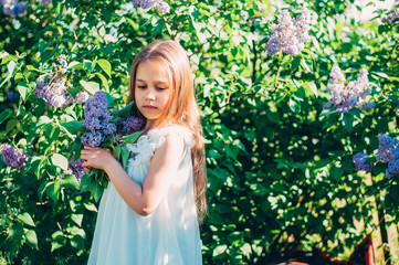 Beautiful girl enjoying the smell of lilacs. Cute model and flowers. The concept of aromatherapy and spring
