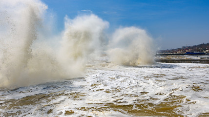 Storm at Black sea coast in Odessa, Ukraine. Huge waves are crashing and spraying ashore during sunny day