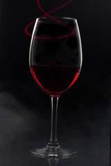 red wine on black background with red light and smoke