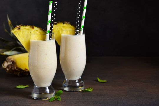 Milk cocktail with vanilla ice cream, pineapple and mango on a dark background.