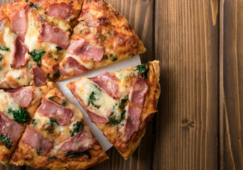 Homemade pizza with spinach, smoked ham. wooden background, copy space.